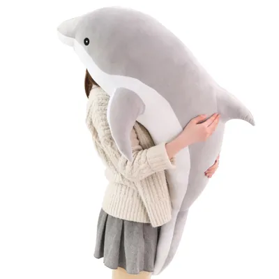 A person is holding a large plush dolphin toy.