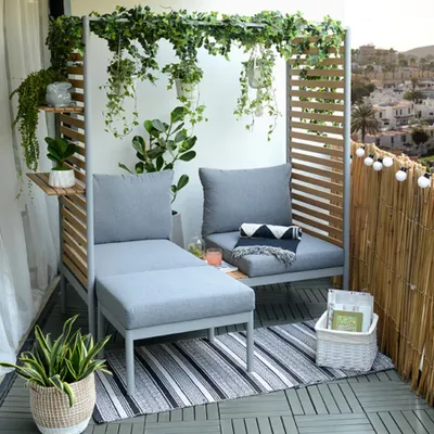A cozy balcony lounge set with plants and a view of buildings.