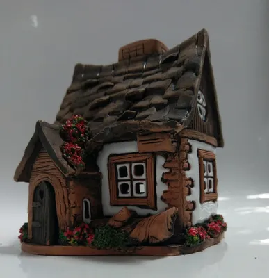 Ein kleines, rustikales Hauses, detailliert gestaltet, mit einem schrägen Dach aus dunklen Ziegeln.