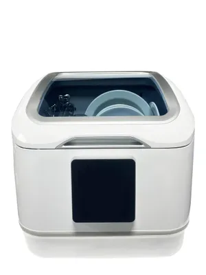 A white tabletop dishwasher with a transparent lid, showing plates and cutlery inside.