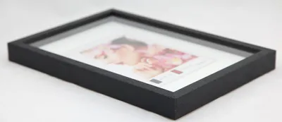 A black wooden picture frame with a white mat and a picture inside, shown at an angle on a white background.