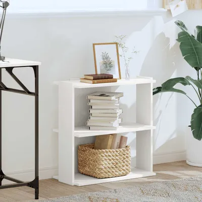A white shelving unit with books and a basket on it, placed next to a desk and a large plant.