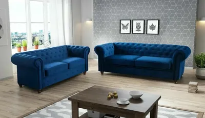 A living room scene with two blue velvet Chesterfield sofas and a coffee table.