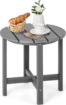 A small, round, gray side table with a basket of bread, a cup and saucer, and a small vase with flowers on top.