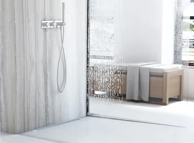 A modern bathroom shower with a sleek shower head and a wooden bench with a towel.
