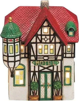 A ceramic miniature hotel building, illuminated from within, with a red tiled roof and black and white half-timbered facade.