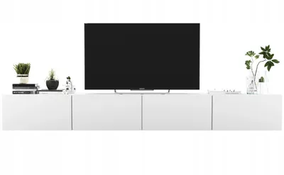 A modern white TV console with a wall-mounted TV and decorative items.