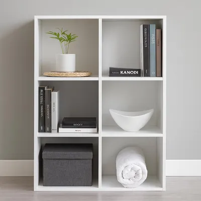 A white cube shelf unit with various items on its shelves.
