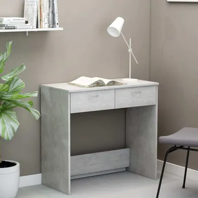 A desk with a book and a lamp on it, next to a plant and a chair.