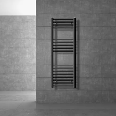 A black radiator is mounted on a gray tiled wall in a modern bathroom setting.