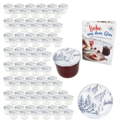A collection of empty glass jars with decorative lids, a single filled jar, a recipe book, and a decorative plate, all with a winter mountain theme.