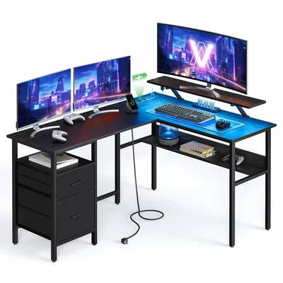 A gaming desk setup with multiple monitors, controllers, and LED lighting.