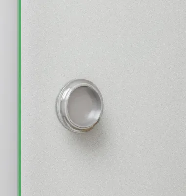 A close-up of a silver door handle on a light gray textured surface.