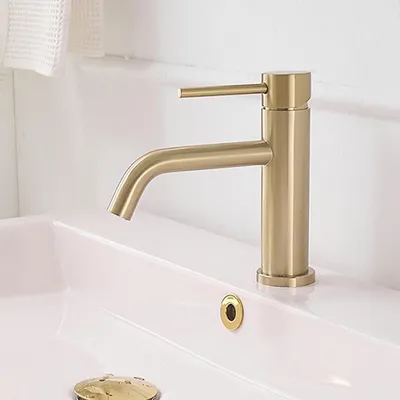 A close-up shot of a gold faucet on a white sink.