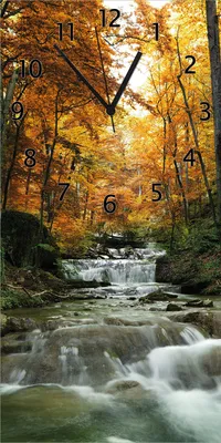 Produktbild von Wallario Design Wanduhr bedruckt, Größe 30 x 60 cm, Motiv: Kleiner Bach über Steine im Herbstwald