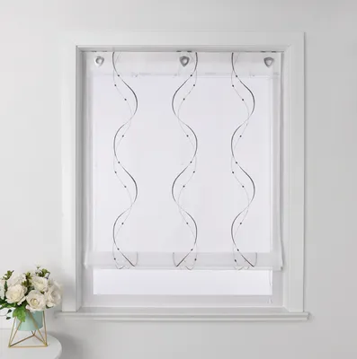 A white window with a sheer curtain featuring a wavy embroidered pattern. A small bouquet of white flowers in a teal pot sits on a white surface to the left.