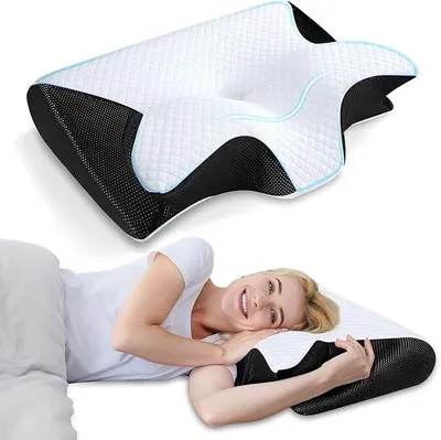 A woman is lying on a bed, smiling and resting her head on an ergonomic pillow.