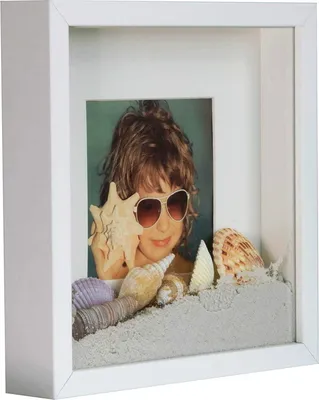 A shadow box frame with a photo of a child wearing sunglasses and holding a seashell, surrounded by sand and more seashells.