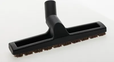 A black vacuum cleaner attachment with brown bristles is placed on a white background.