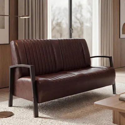A brown leather sofa in a living room setting with curtains and a window in the background.