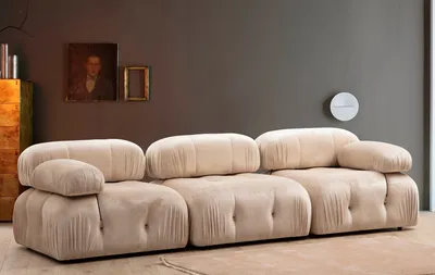 A cream-colored three-seater sofa in a room with a dark gray wall and wooden furniture.