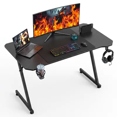 Image de Table de jeu Peviasot, dimensions 120x60 cm, design en forme de Z, aspect carbone, avec porte-boissons et support pour casque