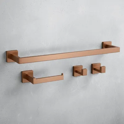 A set of copper-colored bathroom accessories mounted on a gray concrete wall.