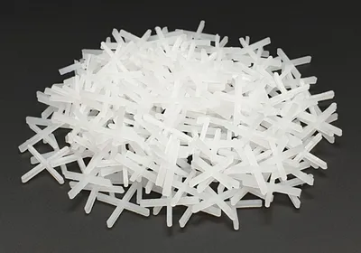 A pile of white tile spacers on a black background.