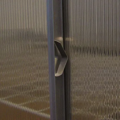 A close-up view of a metal handle on a textured glass surface.