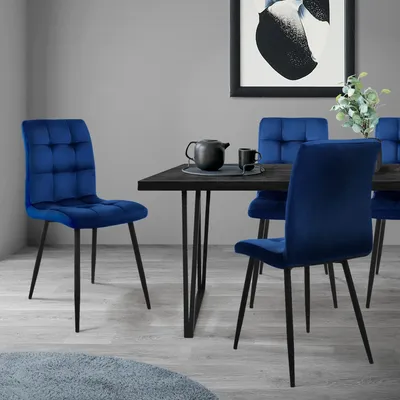 A dining room scene with four dark blue velvet chairs around a dark wood dining table.