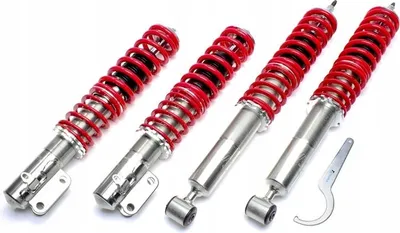 Four red and silver shock absorbers are arranged diagonally on a white background.