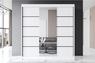 A modern white sliding door wardrobe with black accents is shown in a minimalist interior.