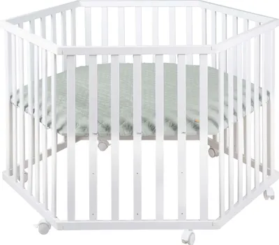 A white hexagonal playpen with a green padded mat inside, shown from a slightly elevated angle.