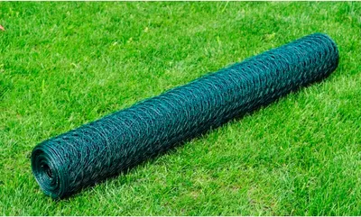A roll of dark green wire mesh fencing lies on a green lawn.