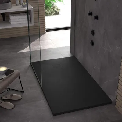 A modern bathroom with a black shower tray, gray tiled walls and floor, and a glass shower enclosure.