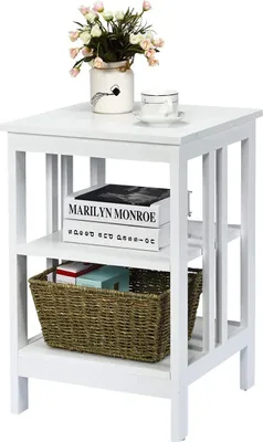 A white three-tiered side table with a basket and books on the shelves, and a vase of flowers and a cup on top.
