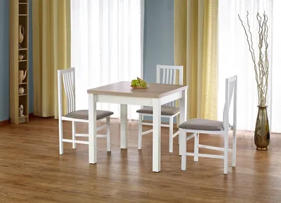 A dining table with three chairs in a room with yellow curtains and a blue wall.