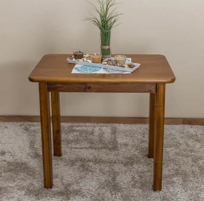 A wooden table with a tray of candles and a plant on it, placed on a fluffy rug.