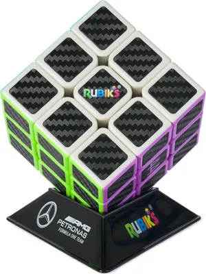 A Rubik's cube with a carbon fiber pattern on a black stand with Mercedes-AMG Petronas Formula One Team branding.