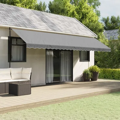 A grey awning is extended over a wooden deck attached to a house, with outdoor furniture visible.