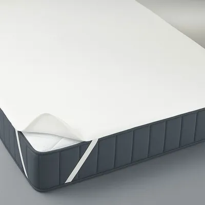 A mattress with a white mattress protector pulled back slightly on one corner to show the mattress underneath.