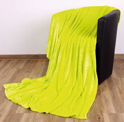 A lime green blanket draped over a black armchair in a room with wooden floors and a white wall.