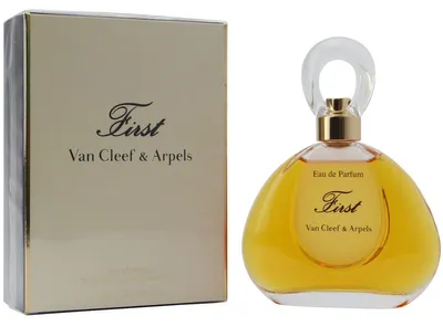 Eleganter Flakon von First Van Cleef & Arpels mit goldener Flüssigkeit und rundem Klardeckel, daneben die passende goldene Parfumverpackung.