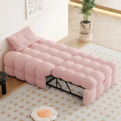 A pink upholstered sofa bed is displayed in a room, with a pillow at one end.