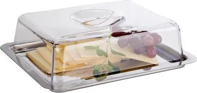 A cheese platter with sliced cheese and grapes under a clear plastic dome on a stainless steel tray.