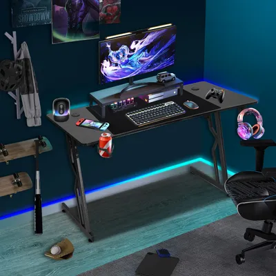 A gaming desk setup in a room with posters on the wall and RGB lighting.