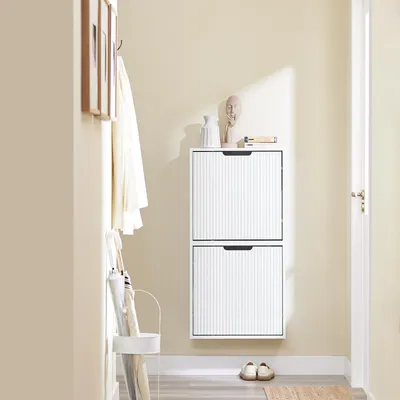 A narrow hallway with a white shoe cabinet, coat rack, and umbrellas.