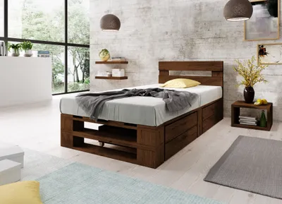 A bedroom scene featuring a wooden bed with storage, a nightstand, and decorative elements.