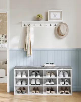 A hallway shoe storage bench and coat rack with a hat, scarf, and shoes.