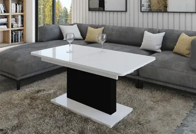 A modern living room with a grey sectional sofa and a white and black coffee table.